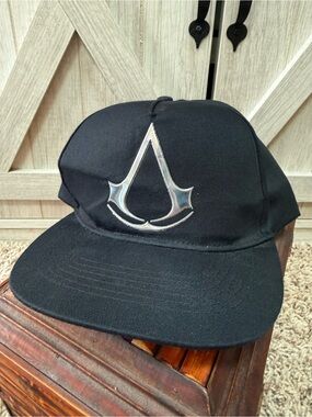 Assassin's Creed Flat Brim Baseball Cap – Black with Shiny Silver InsigniaItem